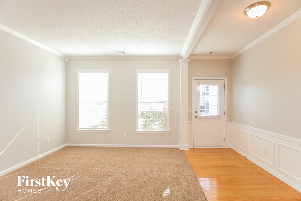 an empty living room with a door and three windows