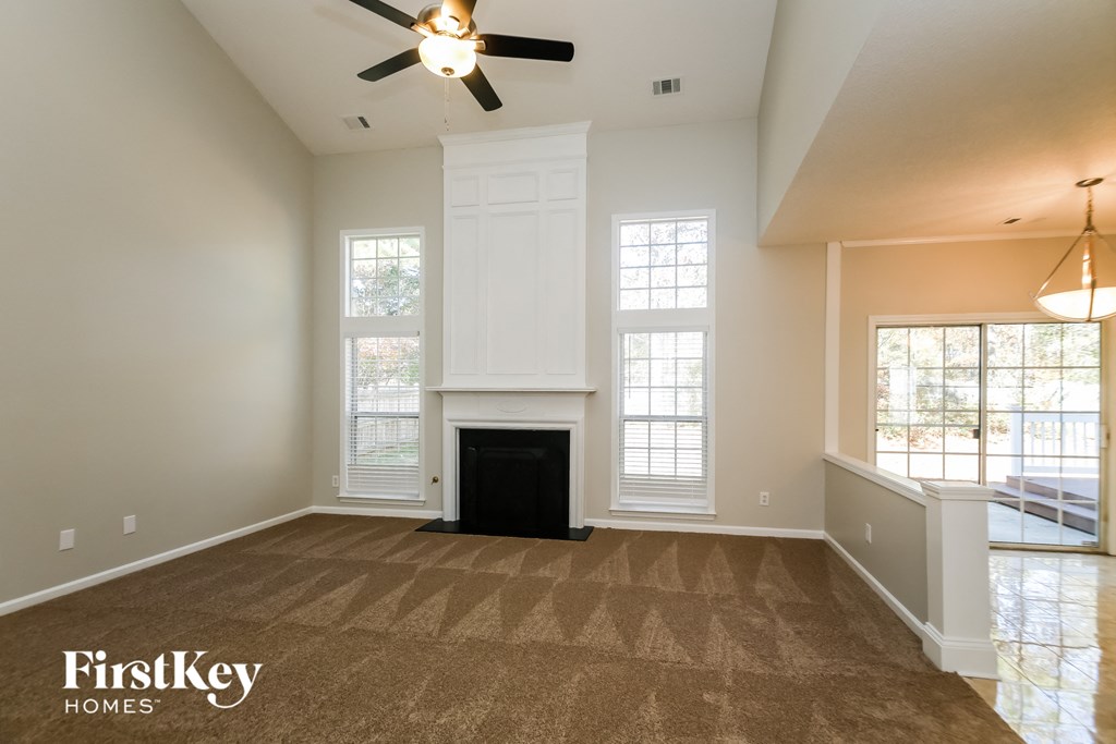 an empty living room with a fireplace and a ceiling fan