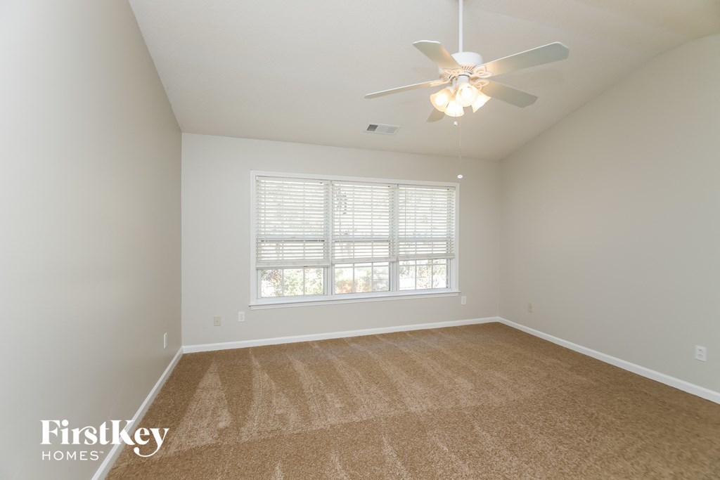 a spacious living room with a large window and a ceiling fan
