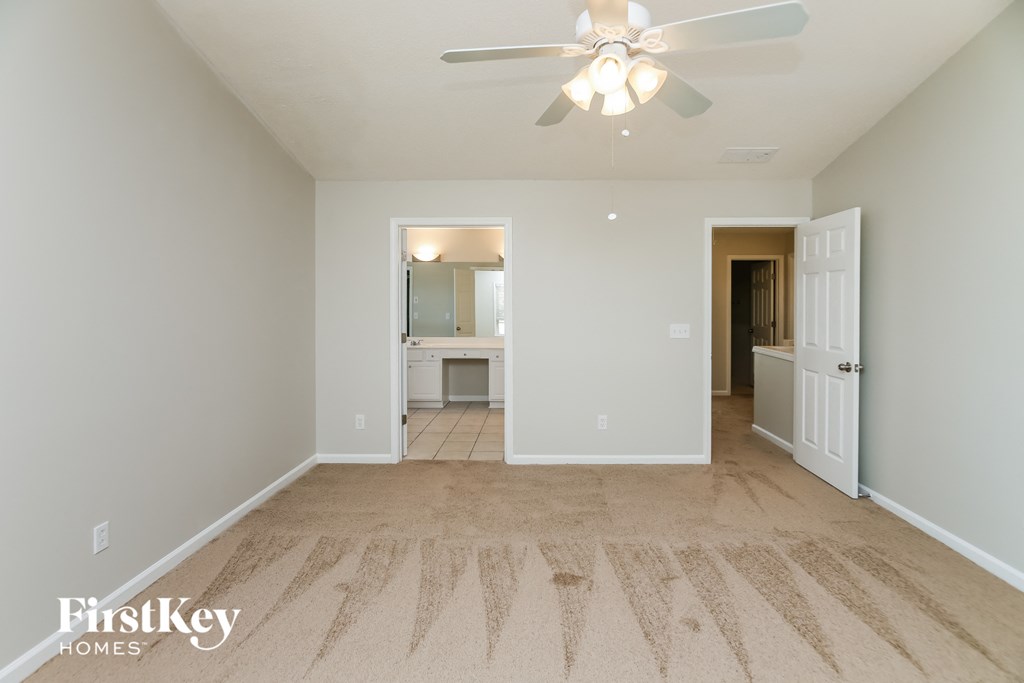 a spacious living room with carpet and a ceiling fan