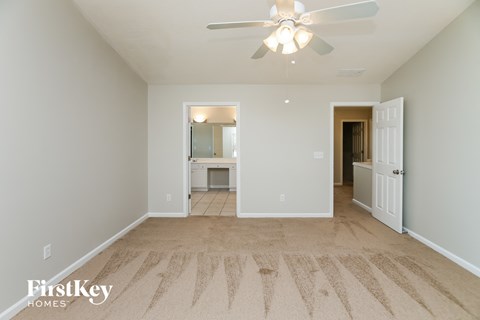 a spacious living room with carpet and a ceiling fan