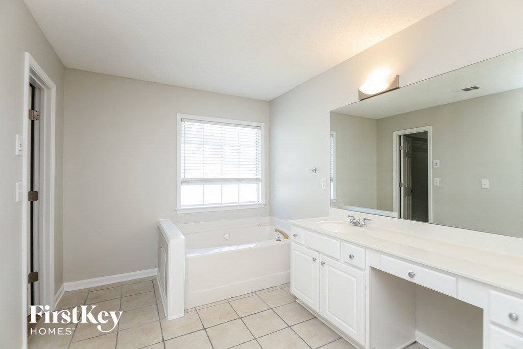 a white bathroom with a tub and a sink and a mirror