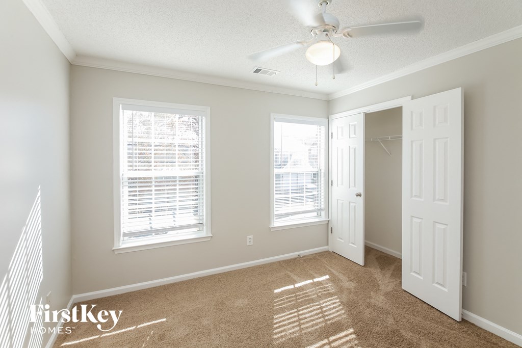 a bedroom with two windows and a ceiling fan
