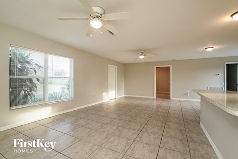 an empty living room with a ceiling fan and a large window