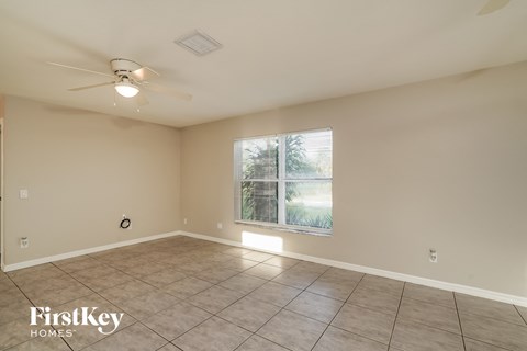 the spacious living room has a ceiling fan and tile flooring