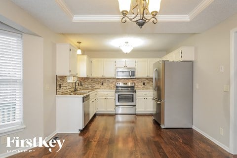 A well-lit kitchen with a refrigerator, oven, and sink.