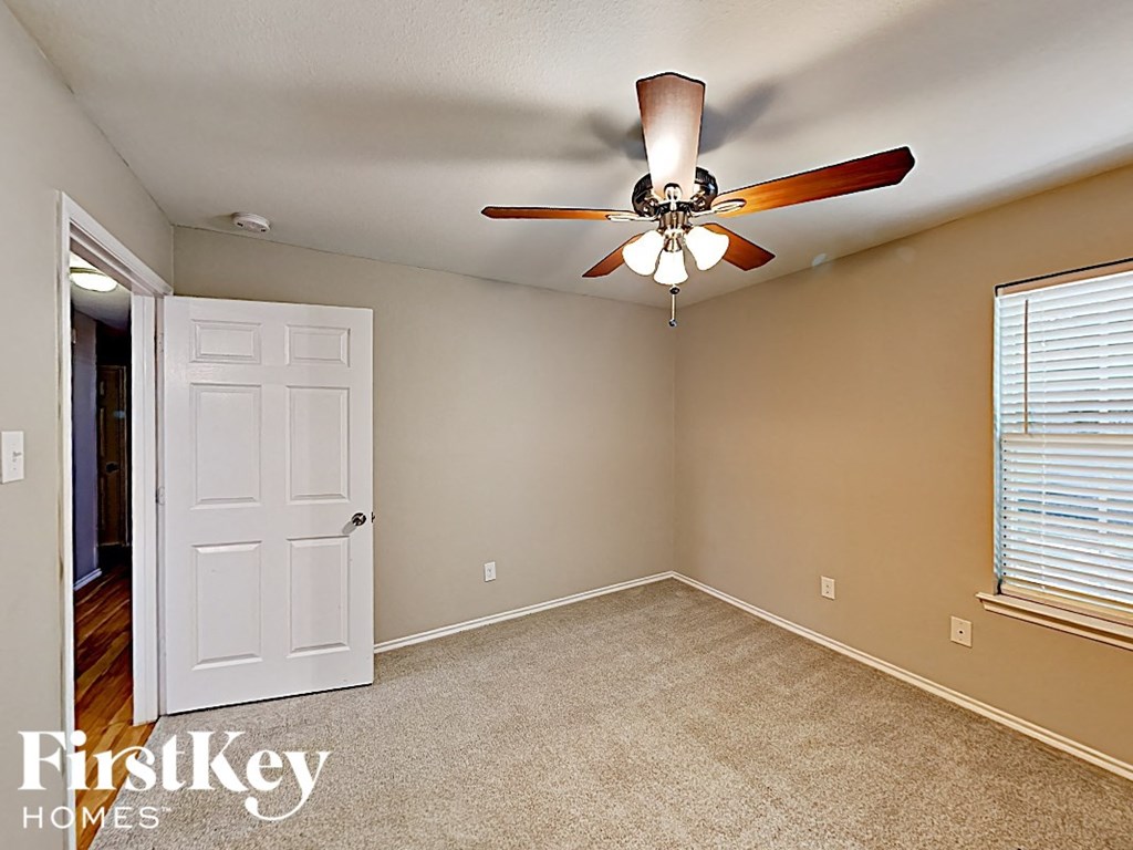 an empty bedroom with a ceiling fan and a door to a closet