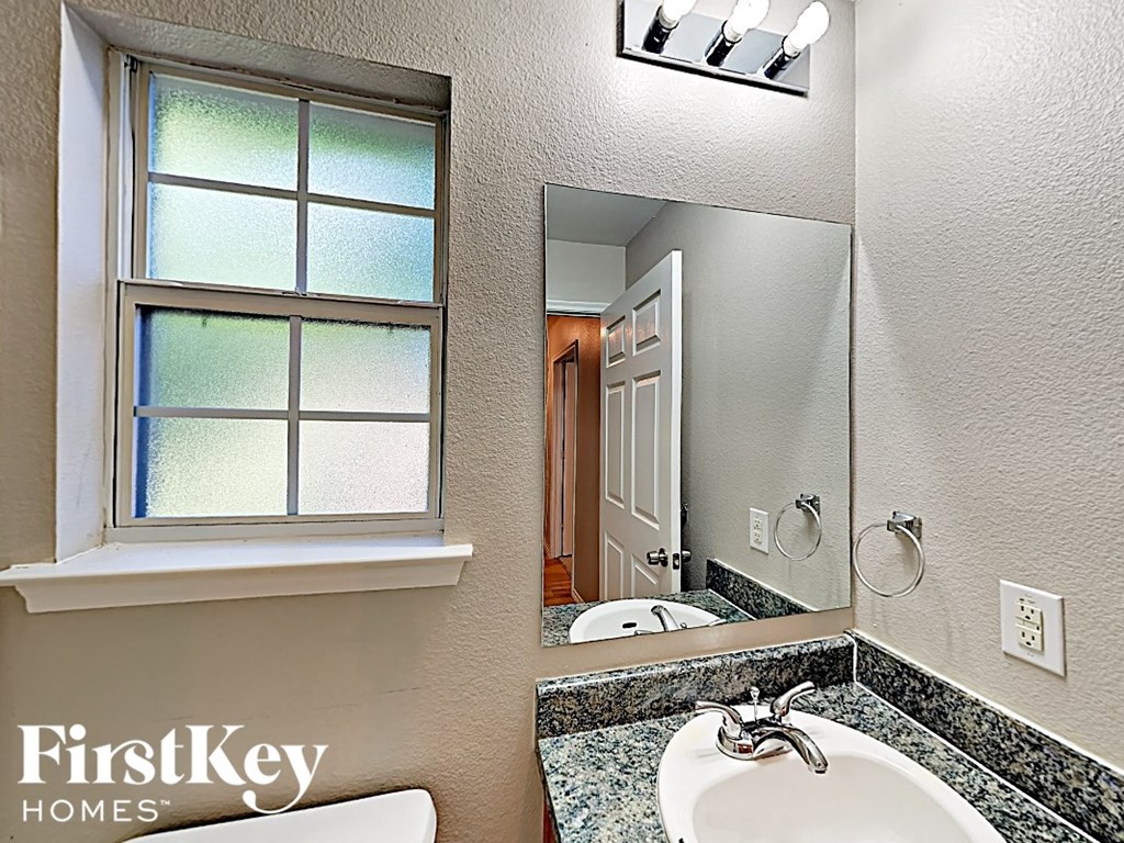 a bathroom with a sink and a mirror and a window