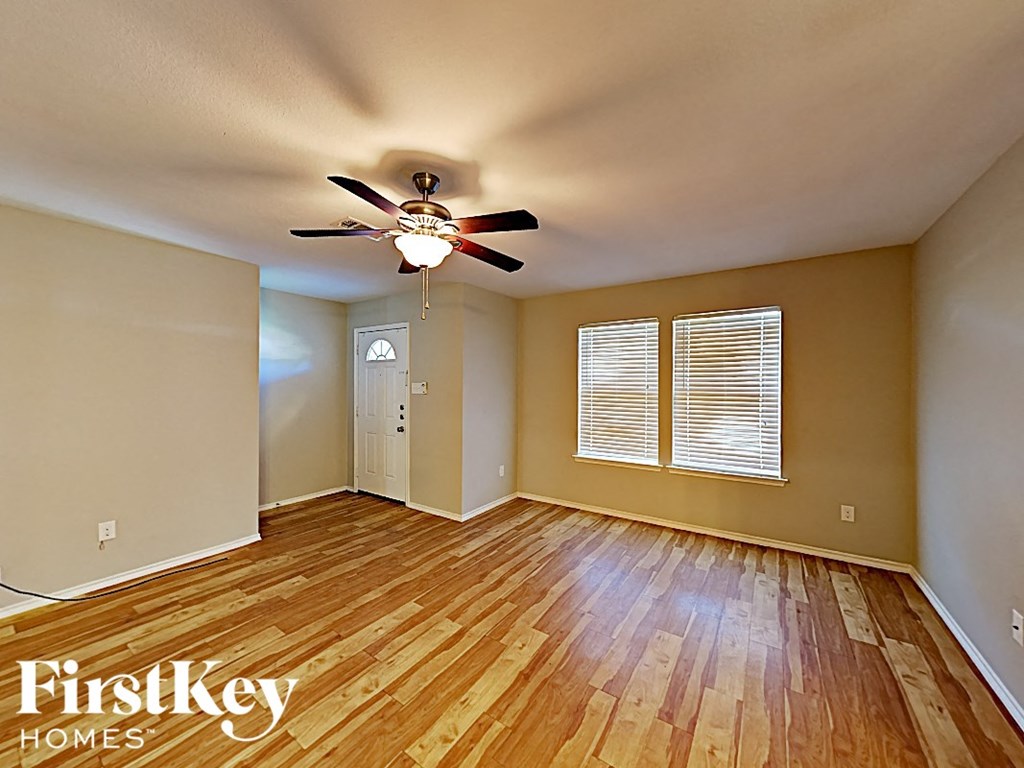 an empty living room with wood floors and a ceiling fan