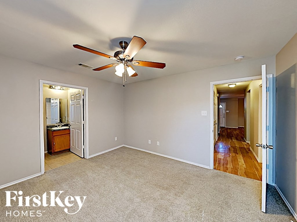 an empty living room with a ceiling fan and a door to a bathroom
