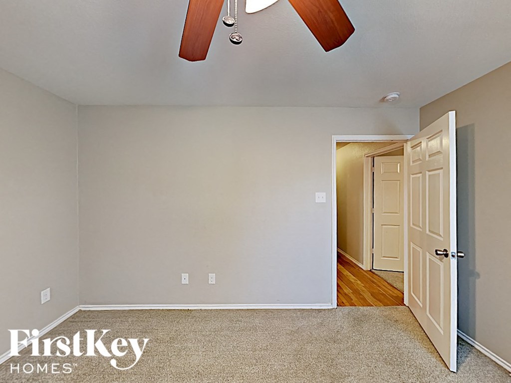 a bedroom with a door to a hallway and a ceiling fan