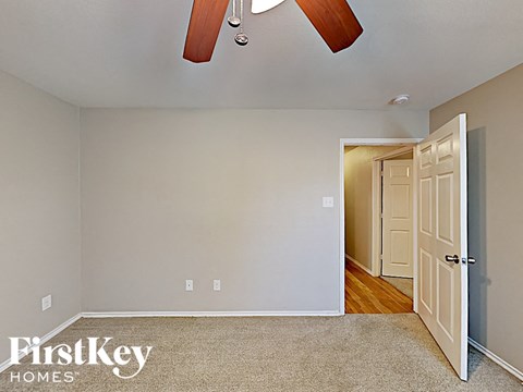 a bedroom with a door to a hallway and a ceiling fan