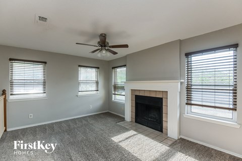A spacious living room with a fireplace and a ceiling fan.