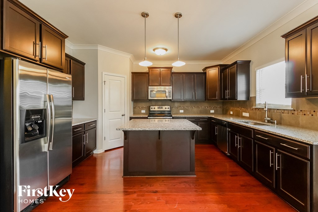 A kitchen with dark wood cabinets and a stainless steel refrigerator.