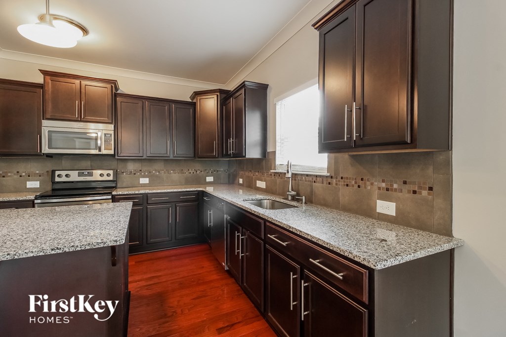 A kitchen with dark brown cabinets and a granite countertop.
