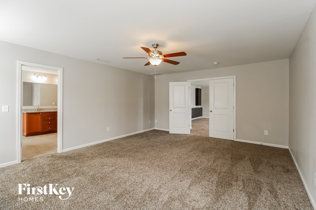 A spacious room with a carpeted floor and a ceiling fan.