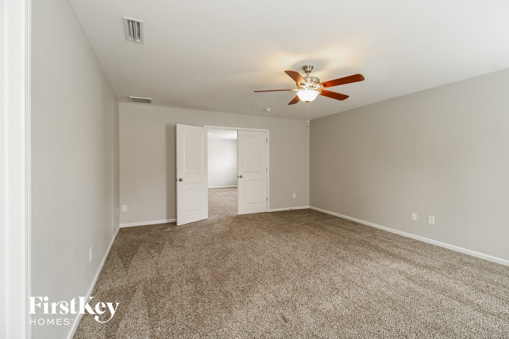 A spacious room with a ceiling fan and carpeted floor.