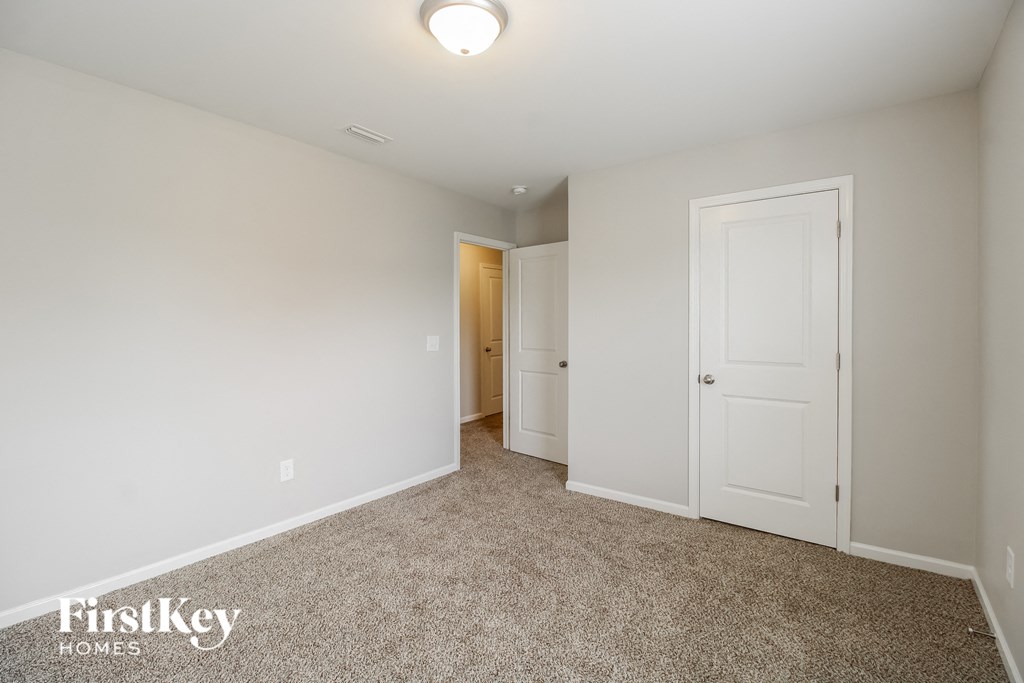 A carpeted room with a door and a light on the ceiling.