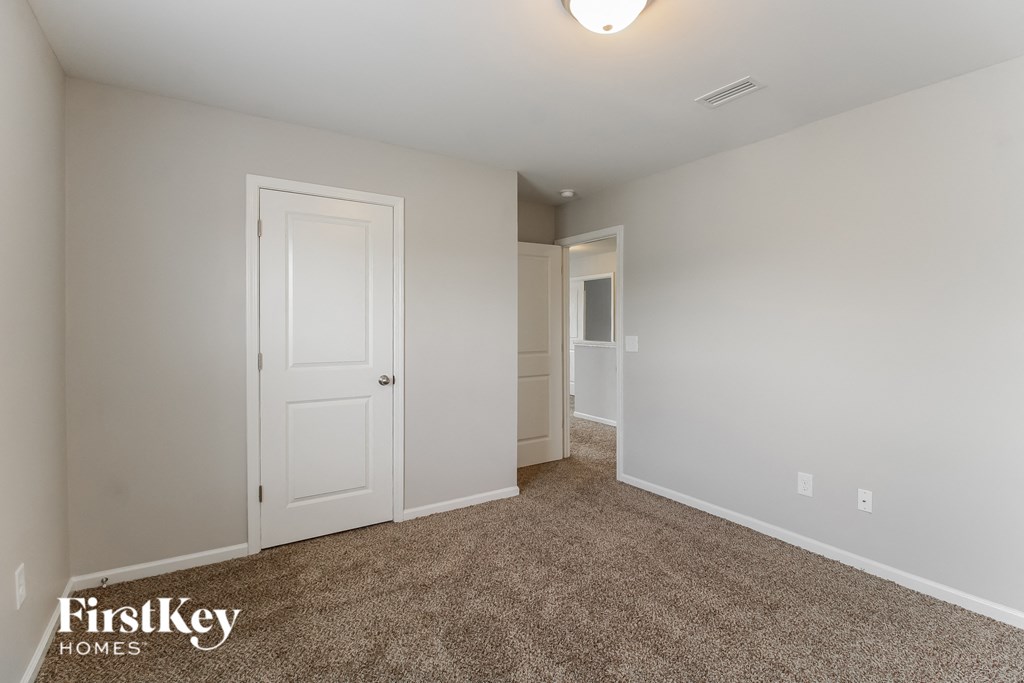 A carpeted room with a door and a window.