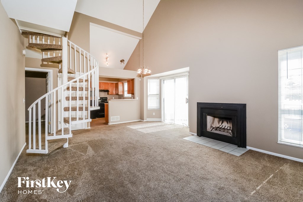 an empty living room with a fireplace and a staircase
