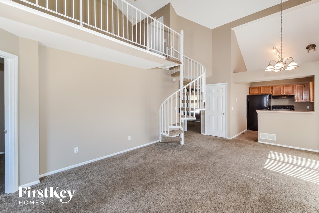a spacious living room with a spiral staircase and a kitchen