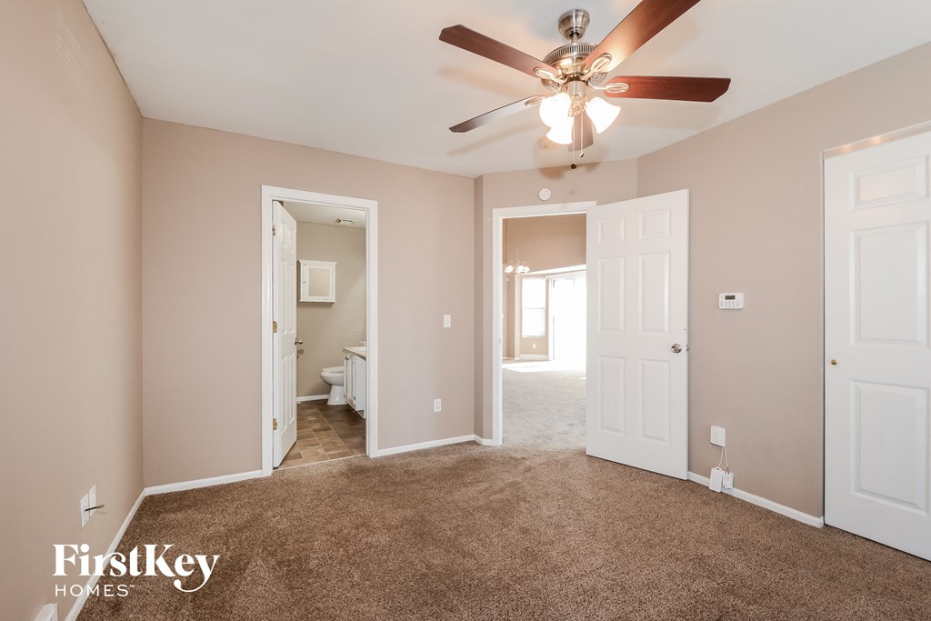 a master bedroom with carpet and a ceiling fan