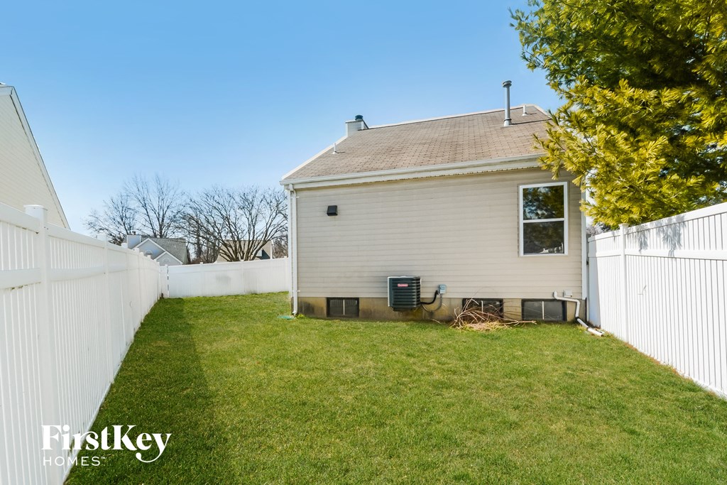 a backyard with a white house and a white fence