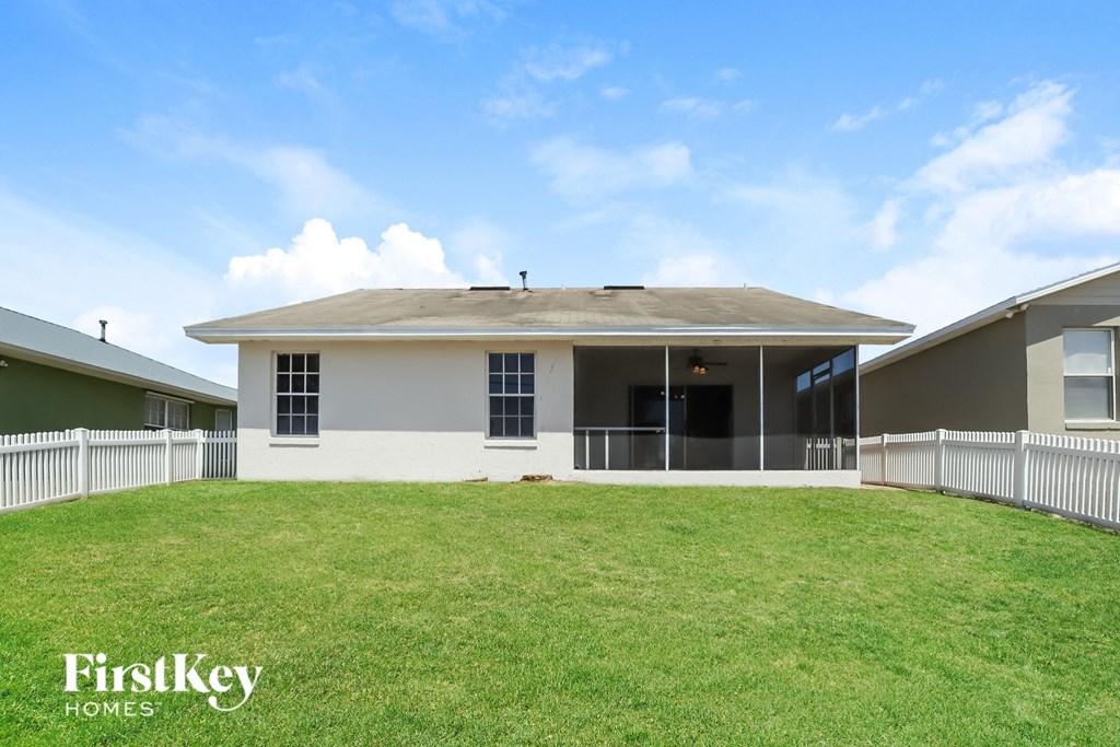A house with a white fence and a grassy yard.
