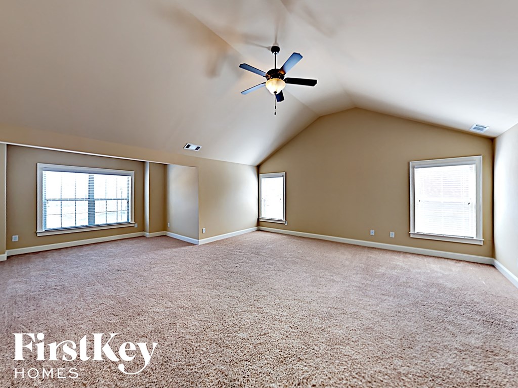 an empty living room with a ceiling fan and two windows