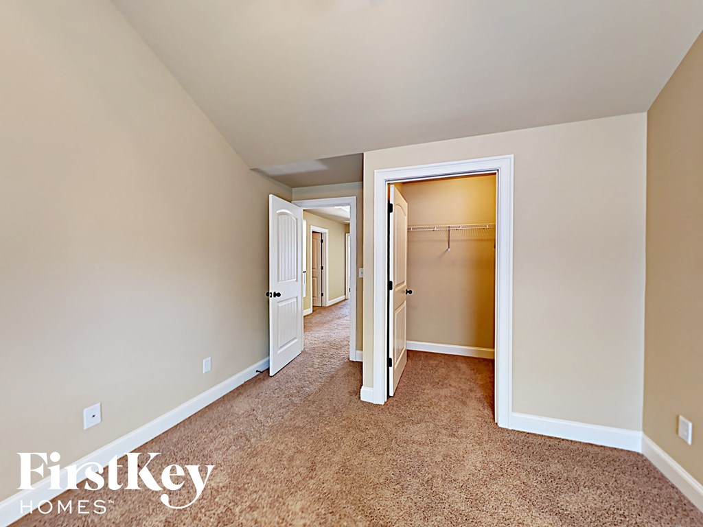 a master bedroom with carpeted flooring and an open door to a closet