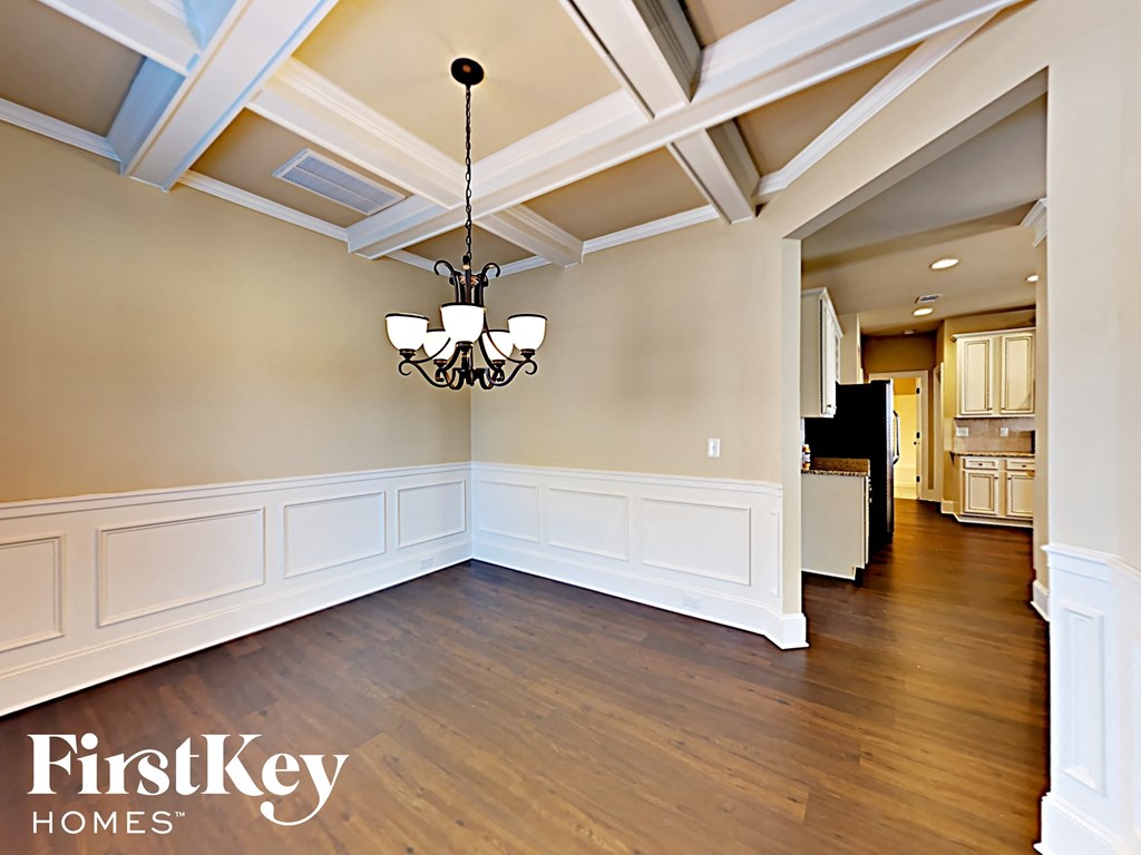 an empty dining room with white walls and a chandelier