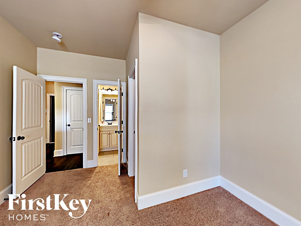 a bedroom with a door to the bathroom and a hallway to the closet and a