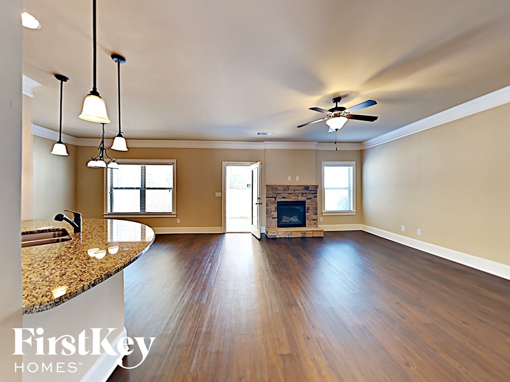 an empty living room with a fireplace and a ceiling fan