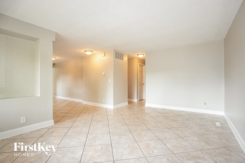 A spacious room with tiled flooring and a doorway leading to another room.