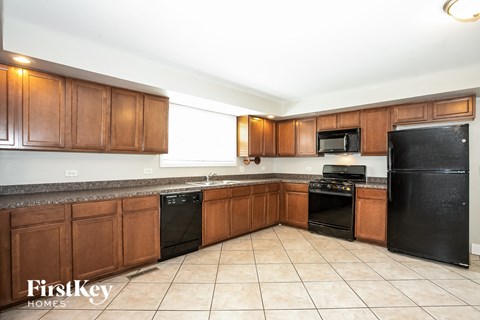 A kitchen with black appliances and brown cabinets.