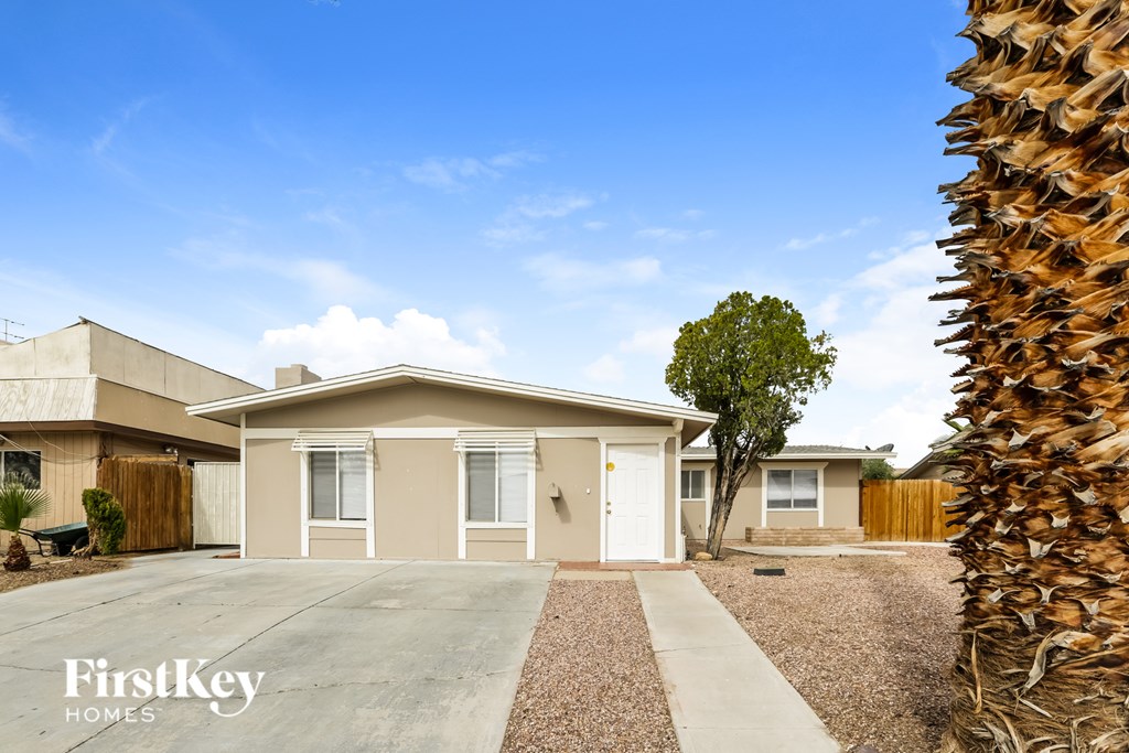 A house with a clear blue sky and a palm tree in the front yard.