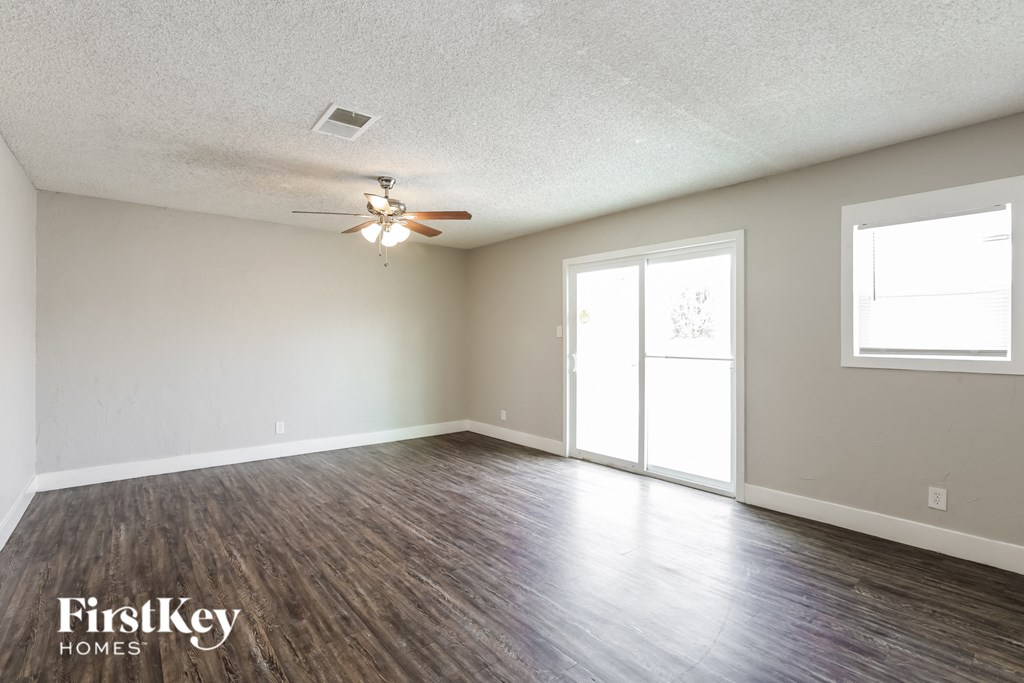 A room with a ceiling fan and wooden flooring.