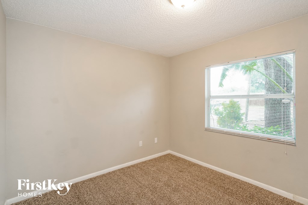 a bedroom with a large window and carpeting