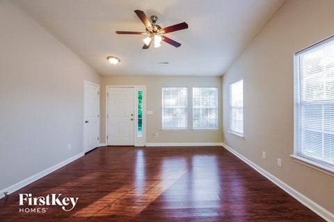 an empty living room with a ceiling fan and windows
