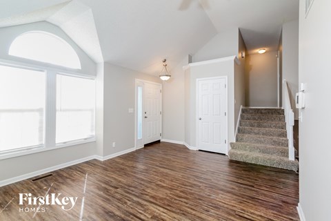 A spacious room with wood flooring and a staircase leading to another room.