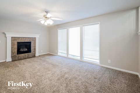 A spacious living room with a fireplace and carpeted floor.