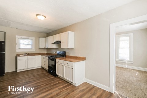 a kitchen with white cabinets and black appliances and a wood floor