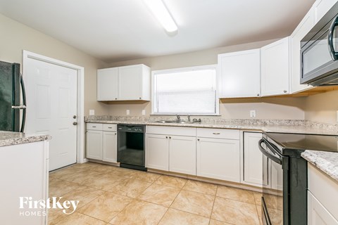 A kitchen with white cabinets and a black fridge.