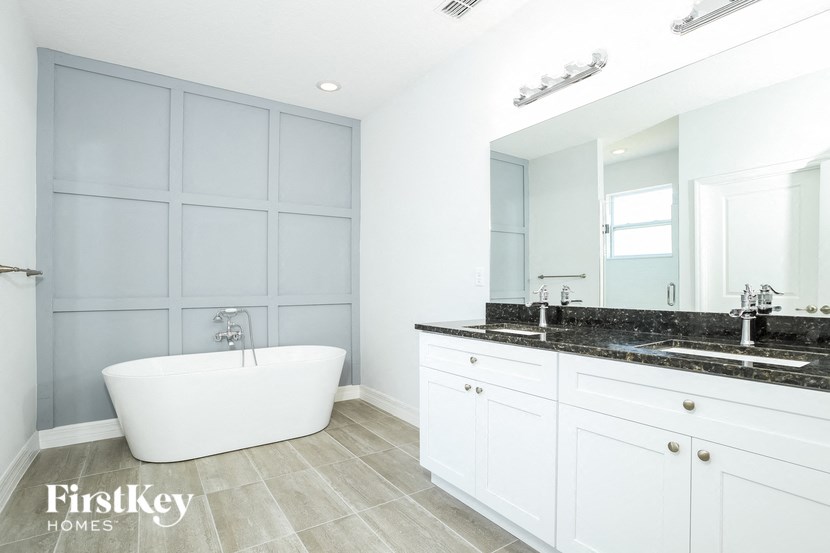 a white bathroom with a tub and a sink and a mirror