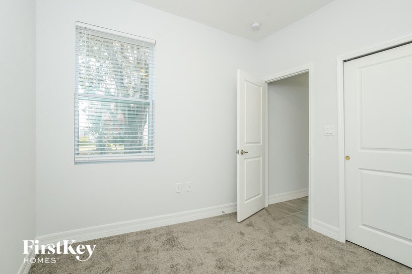 a bedroom with a window and a door and a carpeted floor