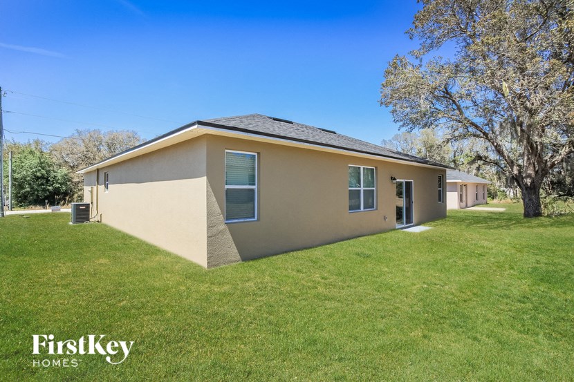 a beige house with a grass yard and trees