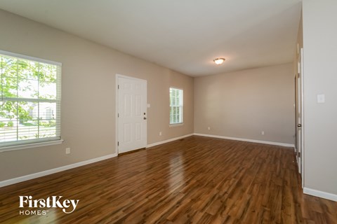 the spacious living room with hardwood flooring and a large window