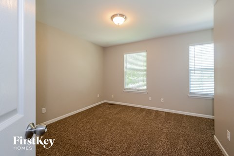 the upstairs bedroom with carpet and two windows