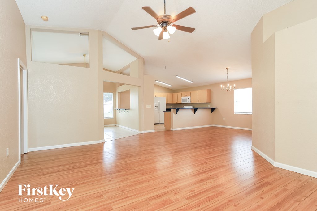 A spacious room with wooden floors and a ceiling fan.