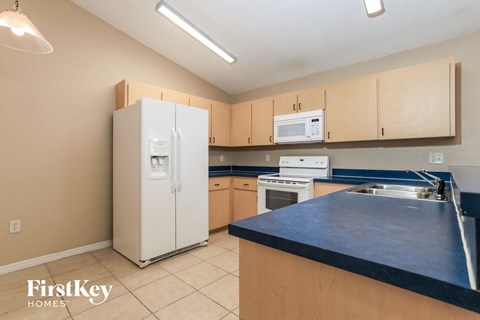 A kitchen with a white fridge and a black counter top.